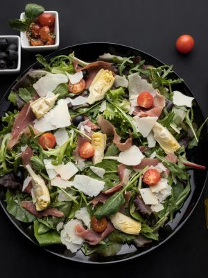 Salade fraîche faites de tomates cerises, olives, pétales de parmesan et émincés de thon